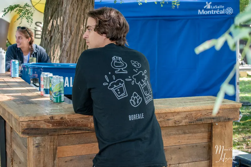 Des visiteurs commandent une bière au comptoir en bois de la brasserie Boréale